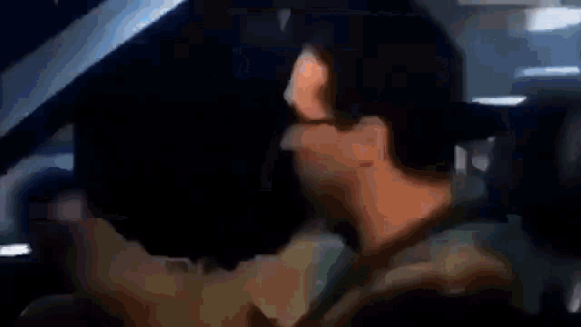 a man is driving a car with headphones on and looking out the window .