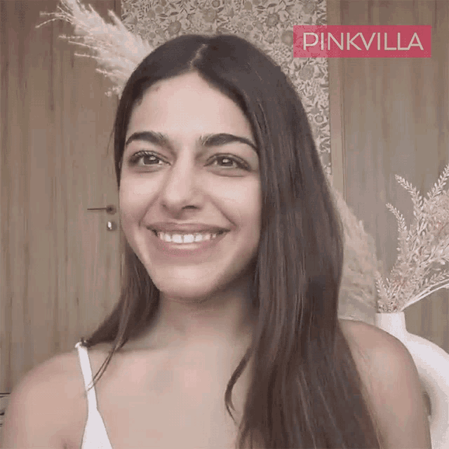 a woman is smiling in front of a pinkvilla logo