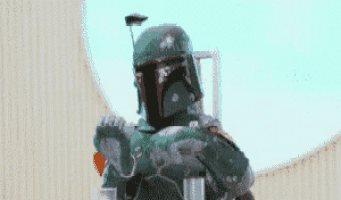 boba fett from star wars is standing in front of a building holding a rifle .