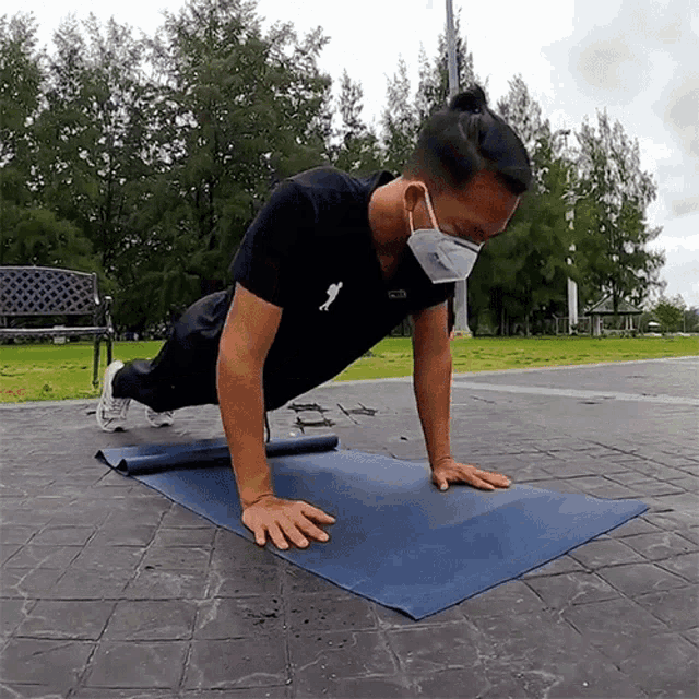 a man wearing a mask is doing push ups on a yoga mat .