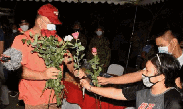 a man wearing a red hat that says chicago is holding a bouquet of roses