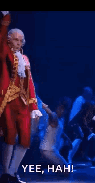 a man in a santa suit is dancing on a stage while holding a piece of paper .