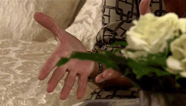 a close up of a person 's hands with a flower in the foreground