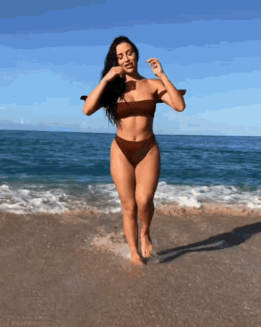 a woman in a bikini stands on the beach