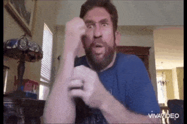 a man with a beard is making a funny face in a living room with a lamp .