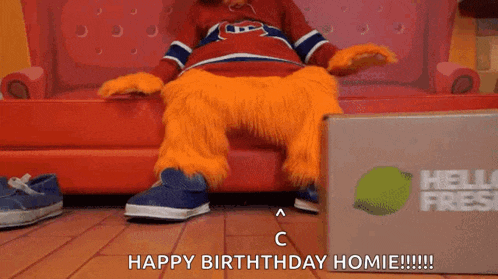 a mascot is sitting on a couch next to a hello fresh box