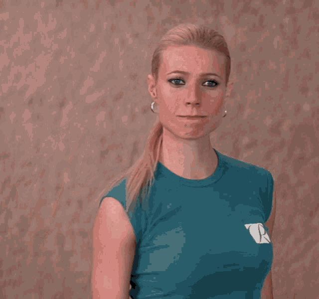a woman wearing a blue t-shirt with the letter p on it salutes