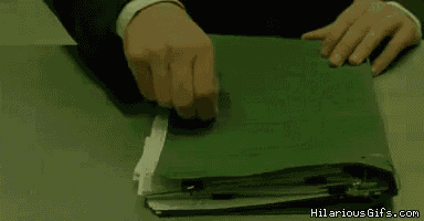 a man in a suit is opening a green binder filled with papers .