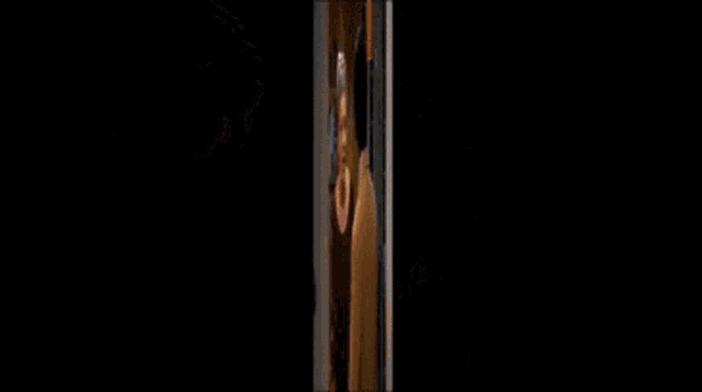 a man is looking at himself in a mirror with a poster on the wall that says " candy "