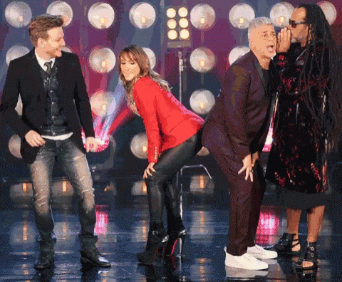 a woman in a red jacket is dancing with two men in suits