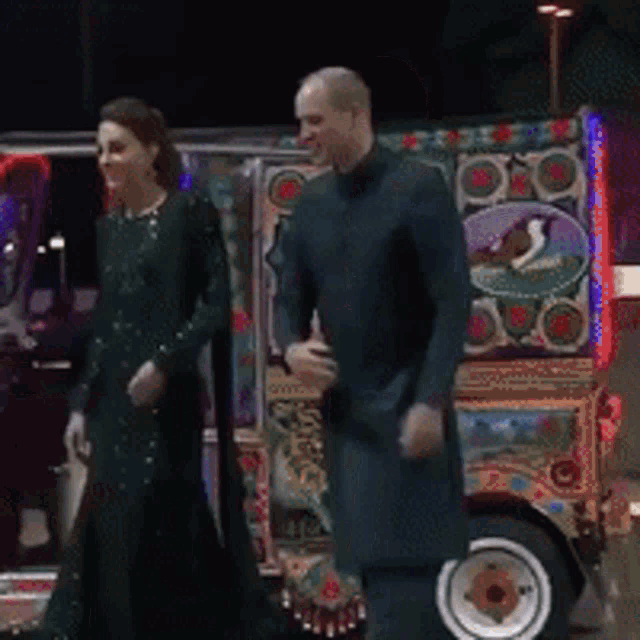 a man and a woman are standing in front of a colorful truck
