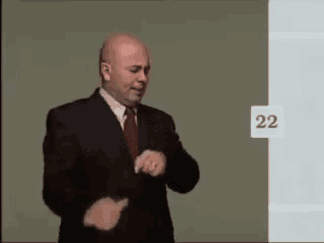 a man in a suit and tie is standing in front of a wall with the number 22 on it