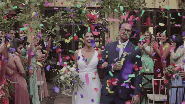 a bride and groom are walking down the aisle as confetti is thrown