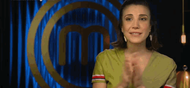 a woman applauds in front of a master chef logo