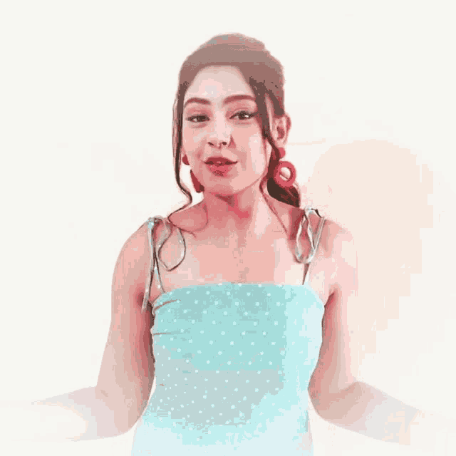 a woman in a blue polka dot dress and red earrings