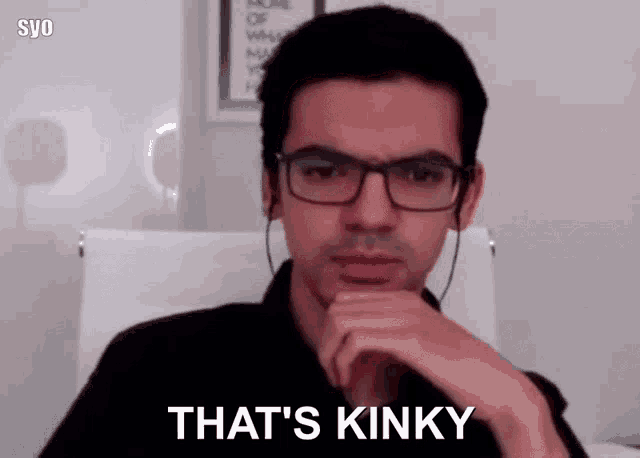 a man wearing glasses is sitting in a chair and says that 's kinky .