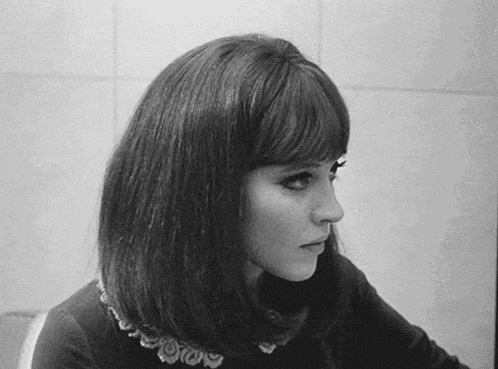 a black and white photo of a woman with short hair and bangs looking at the camera .