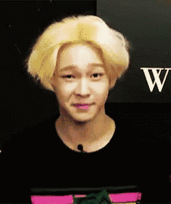 a man with blonde hair is making a funny face in front of a sign that says w.