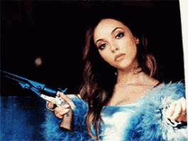 a woman wearing a blue fur coat is holding a gun