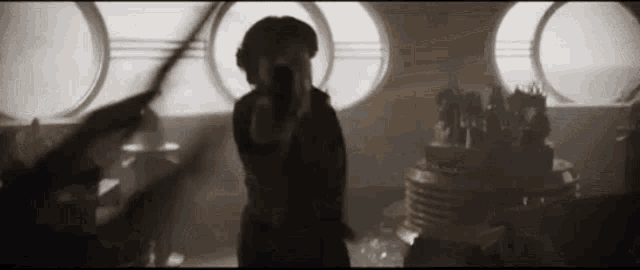 a woman is holding a gun in a dark room with a bunch of windows .