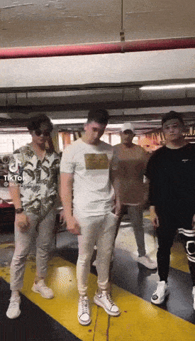 a group of young men are dancing in a parking garage with tiktok written on the bottom right corner