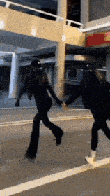 two people are holding hands while walking down the street .