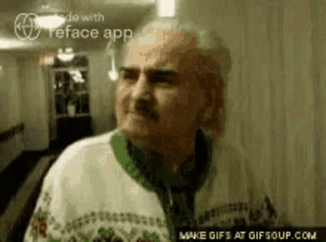 an older man with a mustache is wearing a green sweater and looking at the camera .