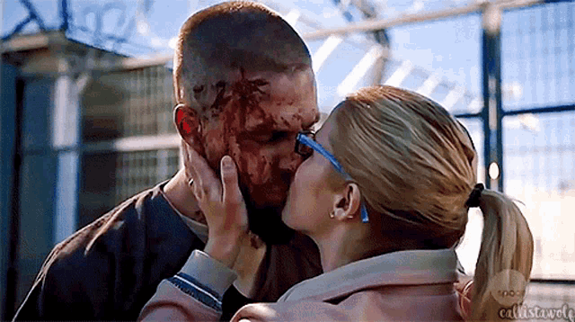a man and a woman are kissing with blood on their faces .
