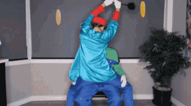 a man in a mario costume holds a hammer over another man 's head