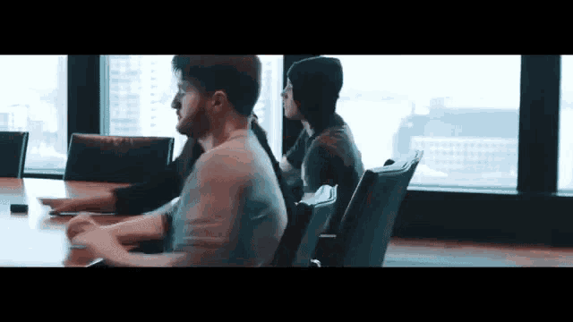 a group of people are sitting at a table with a laptop