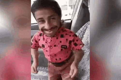 a man with a beard is sitting in the back seat of a car wearing a pink shirt .