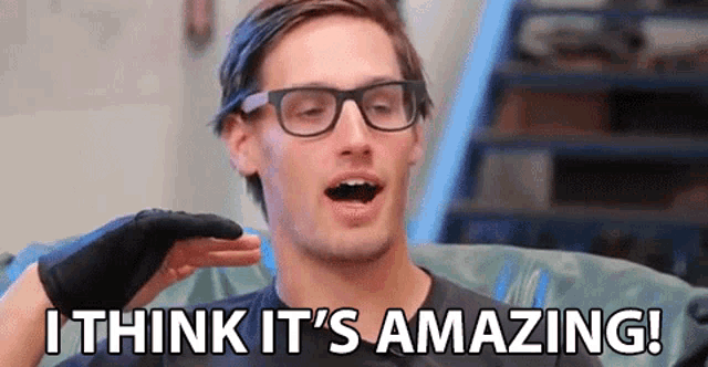 a man wearing glasses and gloves is sitting on a couch and saying `` i think it 's amazing '' .
