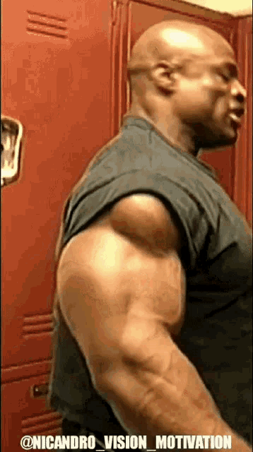 a man with huge muscles is standing in front of red lockers in a locker room .