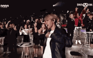 a man singing into a microphone in front of a crowd with mama written on the screen