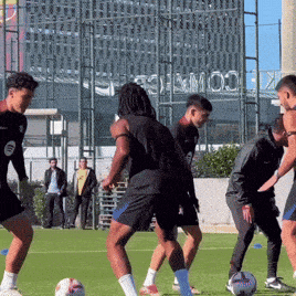 a group of men are playing soccer on a field with a building in the background that says ' stadium '