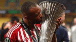 a soccer player is kissing a trophy while wearing a red and white shirt .
