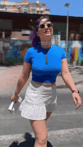 a woman with purple hair wearing a blue crop top and white skirt
