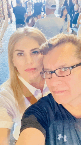 a man wearing under armour takes a selfie with a woman