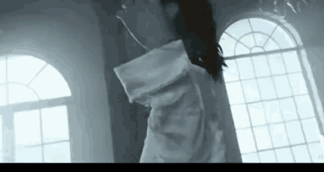 a man in a white shirt is standing in front of a window .