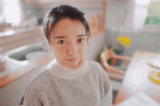 a woman wearing a white sweater looks at the camera
