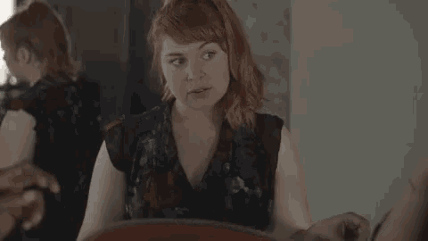 a woman with red hair is sitting in front of a mirror and looking at herself .