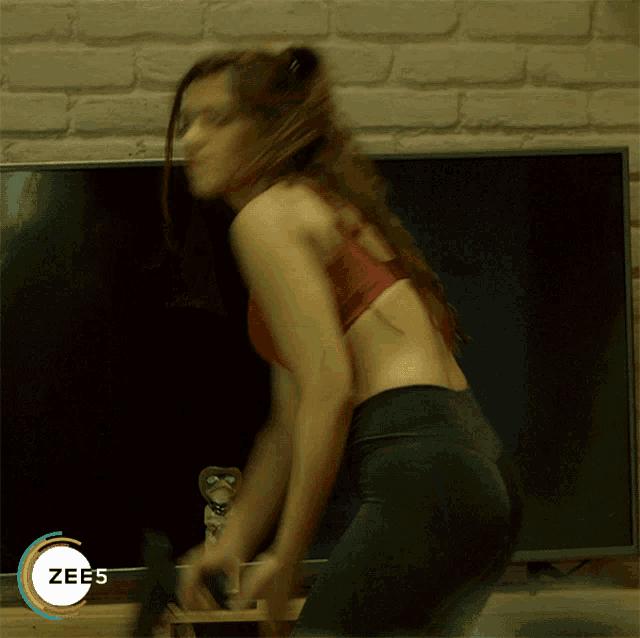 a woman is standing in front of a television with the word zees on the bottom