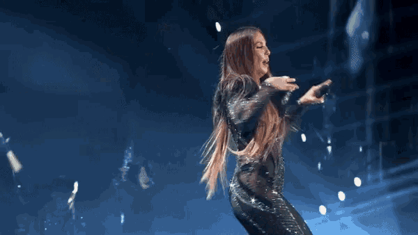 a woman with long hair is singing into a microphone