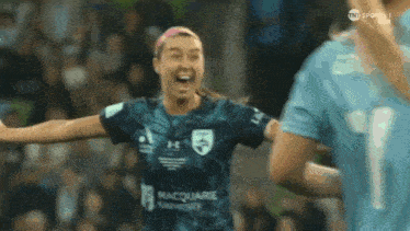 a female soccer player wearing a macquarie university jersey celebrates her goal
