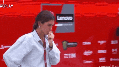 a woman is standing in front of a red wall with the word replay written on it