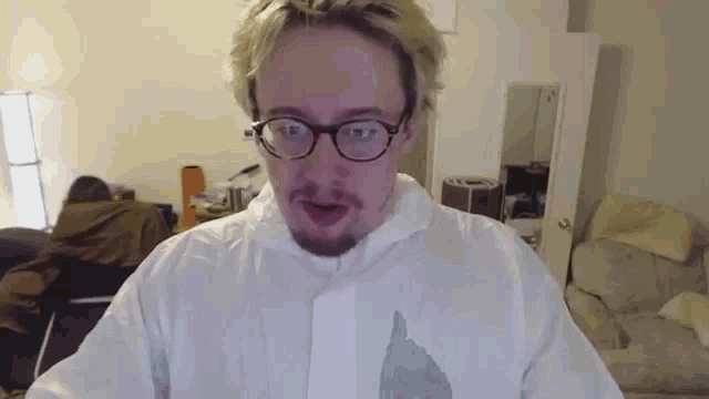 a man wearing glasses and a white shirt is making a funny face