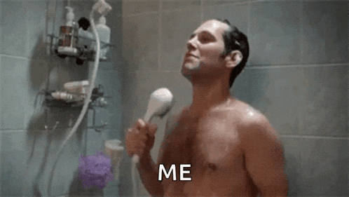 a shirtless man is taking a shower with a shower head and says `` me '' .