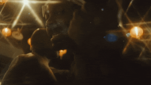 a man and a woman are kissing in a dark room with candles in the background