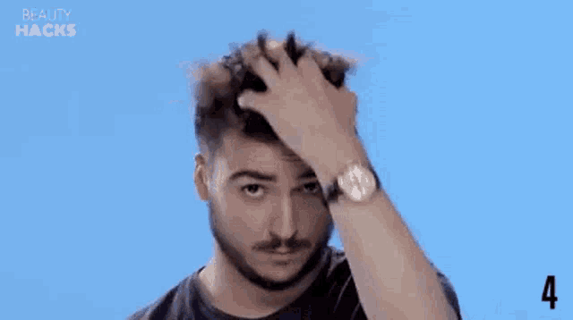 a man with a beard is holding his hair in his hand and looking at the camera .