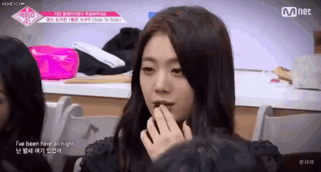 a girl with long black hair is eating something while sitting in a chair